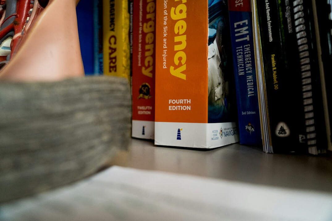 Laptop with online lesson and medical textbooks on a desk